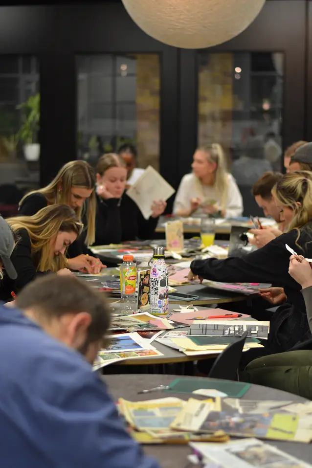 Vidsy team gathered around a long table making collage artwork together