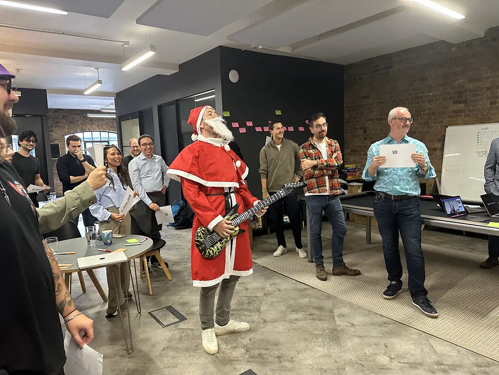 Vidsy teammate dressed as Santa holding an inflatable guitar at the studio Christmas party